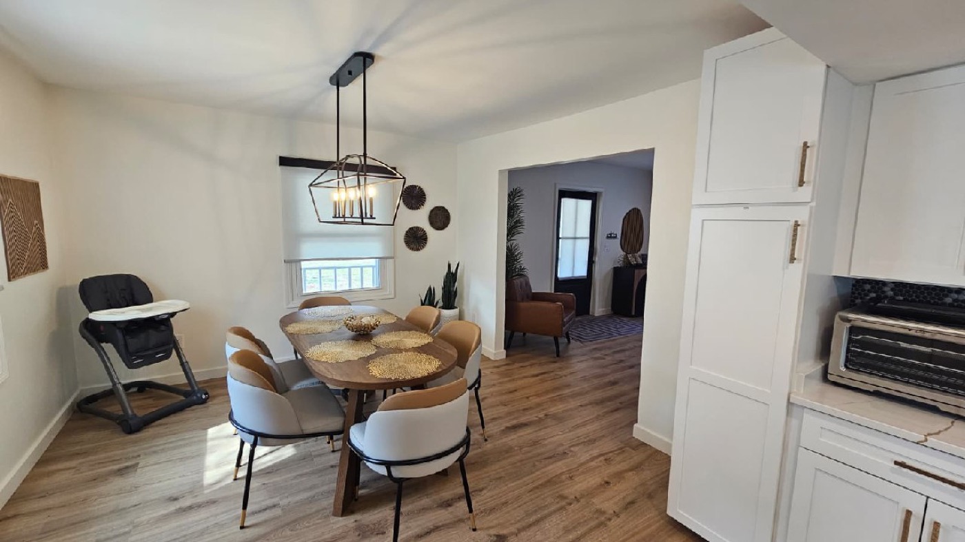 Dining area with round wood table, designer pendant light, and seating for 6